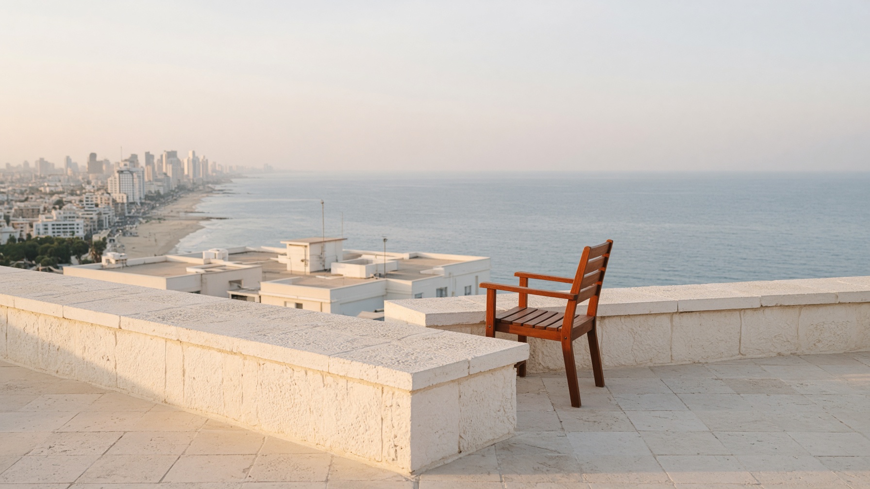 A Tel Aviv rooftop terrace looking west toward the Mediterranean at late afternoon.